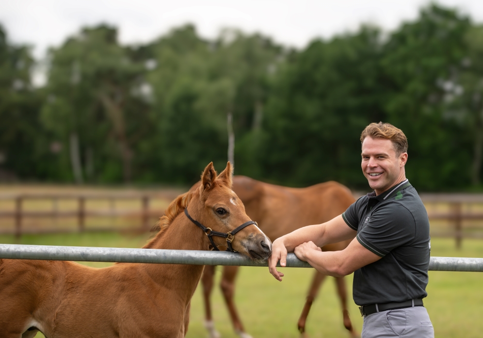 Jeremy LeBlanc stands in a pasture with foals