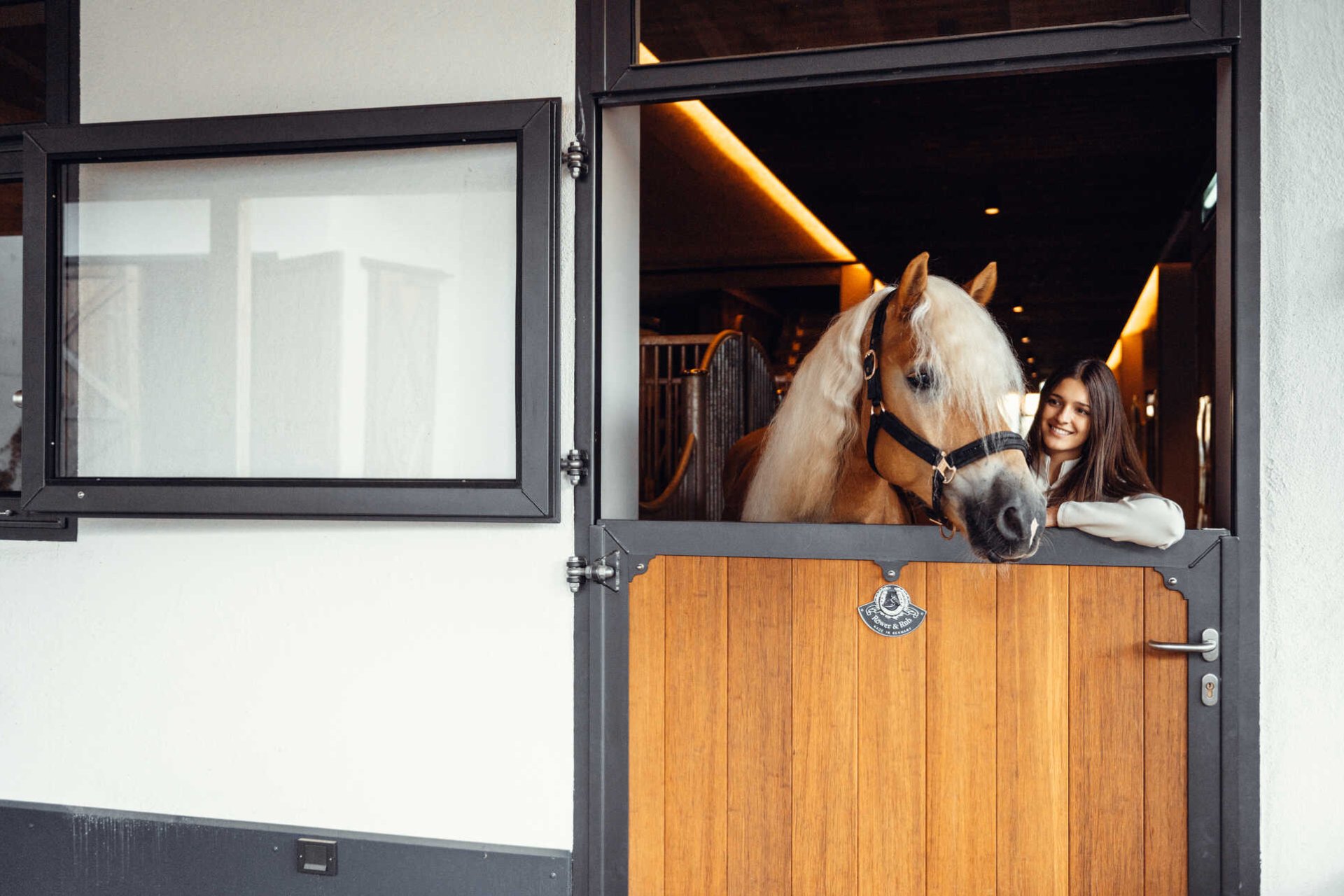 Röwer & Rüb Stalleingangstüren junge Frau mit Pferd schaut durch geöffneter Obertür heraus