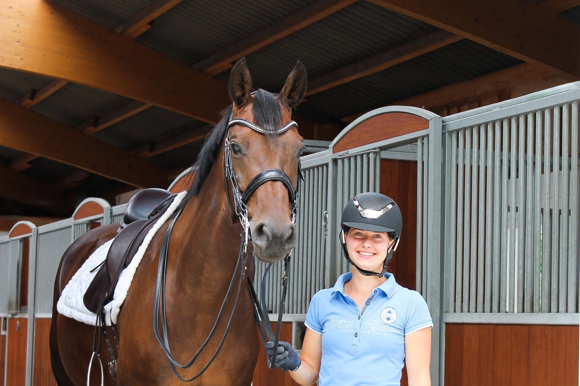 Reiterin und Pferd stehen in Stallgasse mit dem Boxenmodell Modulsystems Hamburg