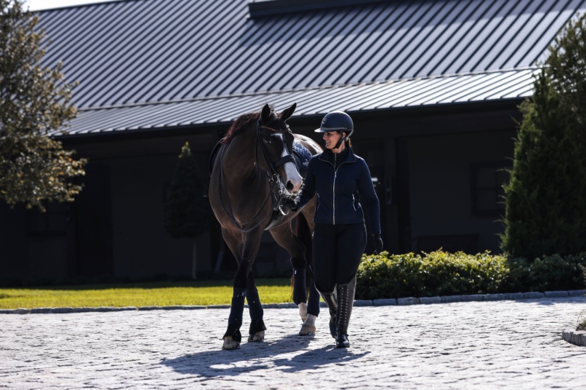 Frau mit Pferd läuft über den Aussenbereich der Reitanlage