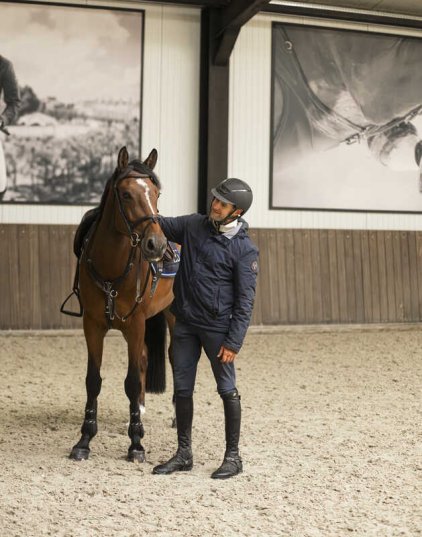 Un cavalier caresse son cheval dans le hall de l'écurie Ehrens